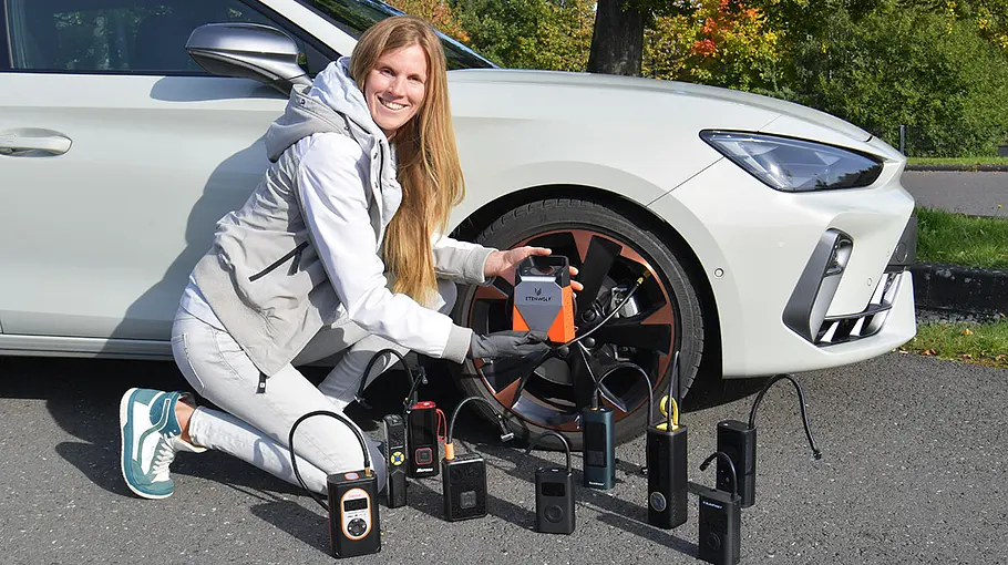 Akku-Luftpumpen im Test Testerin vor einem Cupra Leon mit Akku-Luftpumpen, fotografiert von der Seite.