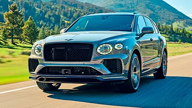 Bentley Bentayga Speed (2025) fährt auf einer Landstraße, Ansicht von vorne links. - Foto: Bentley