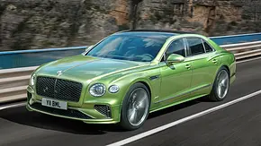 Das Bentley Flying Spur Facelift (2024) fährt über eine Brücke, von vorne links fotografiert. - Foto: Bentley