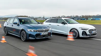 BMW 3er Touring und Audi A5 Avant fahren nebeneinander auf einer Flugzeuglandebahn, von vorne rechts fotografiert. - Foto: Frank Ratering