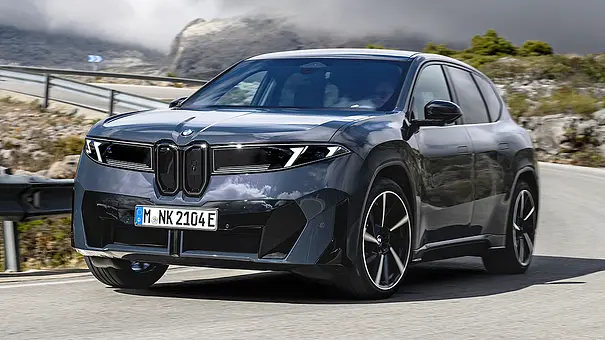 Der BMW iX3 fährt auf einer Bergstraße durch eine Rechtskurve, von vorne links fotografiert. - Foto: BMW