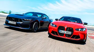 Blick von schräg vorne auf die beiden fahrenden Sportcoupés Ford Mustang Dark Horse und BMW M4. - Foto: Daniela Loof