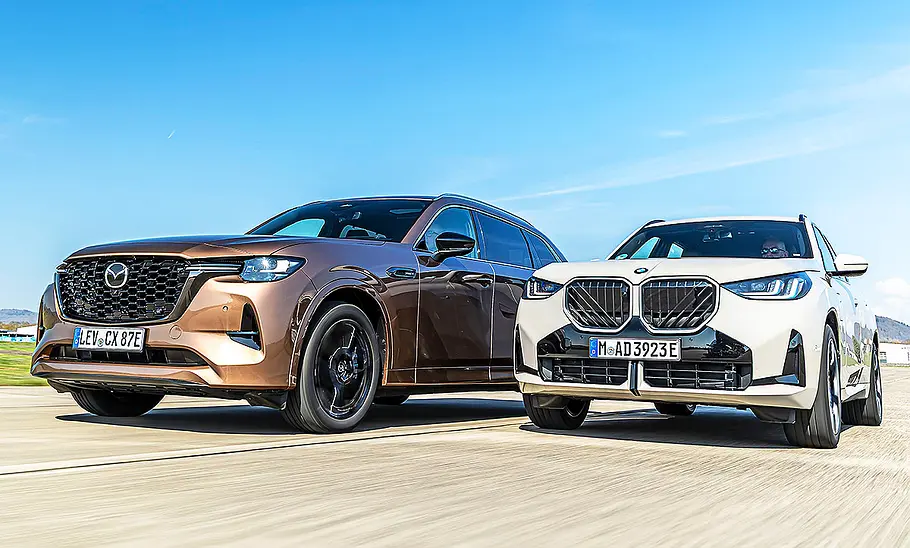 Mazda CX-80/BMW X3 Blick von schräg vorne auf die beiden fahrenden SUV Mazda CX-80 und BMW X3.
