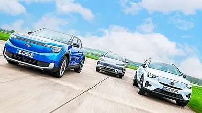 Blick von vorne auf die drei elektrischen Kompakt-SUV Ford Explorer Elektro, BYD Seal U und Volvo EX40, die in Formation af einer asphaltierten Fläche fahren. - Foto: Daniela Loof
