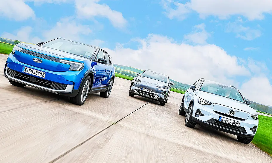 Ford Explorer Elektro/BYD Seal U/Volvo EX40 Blick von vorne auf die drei elektrischen Kompakt-SUV Ford Explorer Elektro, BYD Seal U und Volvo EX40, die in Formation af einer asphaltierten Fläche fahren.