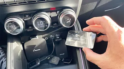 Kabellose Apple CarPlay-Adapter liegen in der Mittelkonsolenablage eines Autos. - Foto: AUTO ZEITUNG