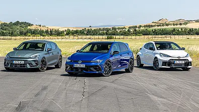 Cupra Leon VZ, VW Golf R und Toyota GR Yaris stehen auf einer asphaltierten Fläche in einer Formation nebeneinander, von vorne fotografiert. - Foto: Frank Ratering