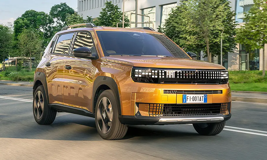 Der Fiat Grande Panda Hybrid (2025) fährt durch eine Stadt, von vorne rechts fotografiert.
