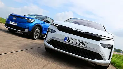 Gruppenbild mit Blick von vorne auf die beiden fahrenden E-SUV Ford Explorer und Skoda Enyaq. - Foto: Daniela Loof