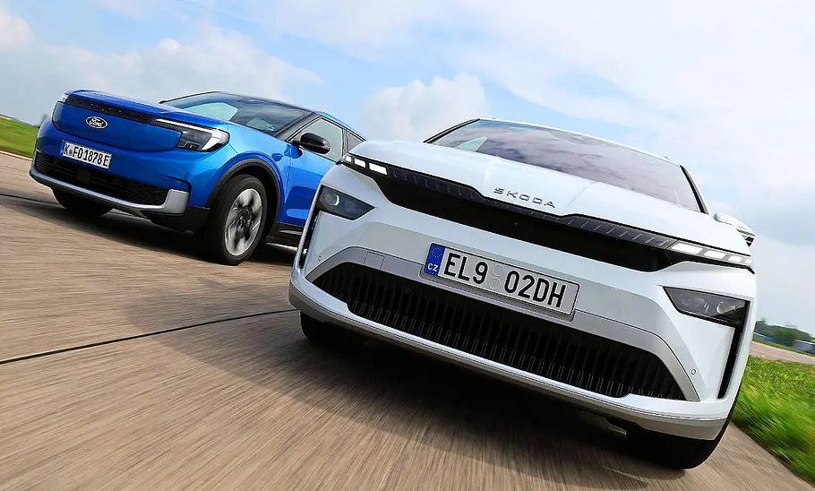 Gruppenbild mit Blick von vorne auf die beiden fahrenden E-SUV Ford Explorer und Skoda Enyaq.