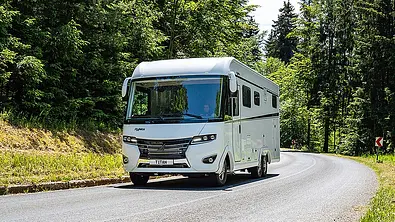Der Frankia Titan auf einer Landstraße durch ein Waldstück fahrend von schräg vorne links. - Foto: Frankia