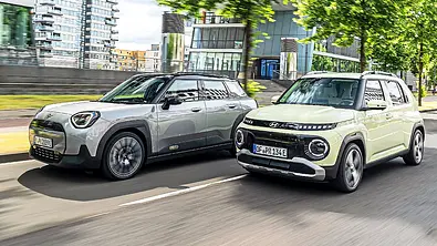 Blick von schräg vorne auf die fahrenden Elektro-Kleinwagen Mini Aceman und Hyundai Inster. - Foto: Frank Ratering