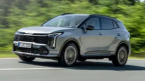 Der Kia Sportage (2025) fährt auf einer Landstraße, von vorne links fotografiert. - Foto: Kia