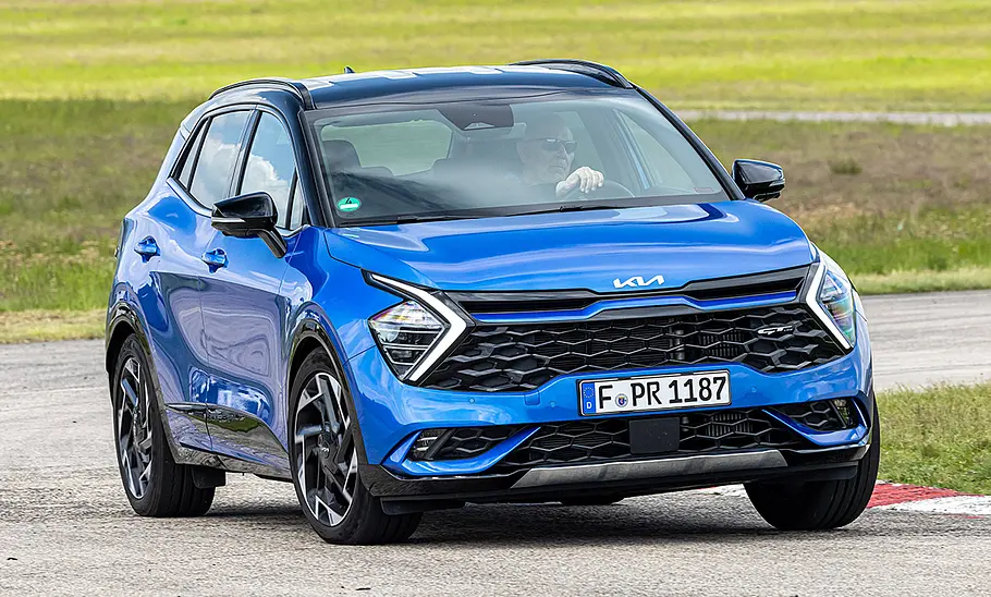 Kia Sportage (2021) Der Kia Sportage (2021) fährt durch eine Linkskurve, von vorne rechts fotografiert.