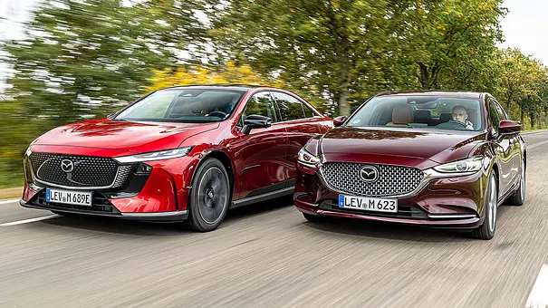 Mazda6e und Mazda6 fahren nebeneinander auf einer Landstraße, von vorne links fotografiert. - Foto: Frank Ratering