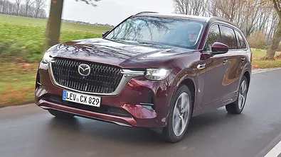 Mazda CX-80 fährt auf einer Landstraße, Ansicht von vorne links. - Foto: Zbigniew Mazar