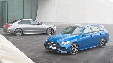 Die Mercedes C-Klasse steht als T-Modell und Limousine nebeneinander vor einem modern gestalteten Gebäude. - Foto: Mercedes
