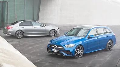 Die Mercedes C-Klasse steht als T-Modell und Limousine nebeneinander vor einem modern gestalteten Gebäude. - Foto: Mercedes
