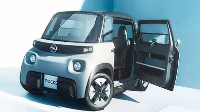 Der Opel Rocks (2025) steht mit geöffneter Fahrertür vor weißem Hintergrund, von vorne links fotografiert. - Foto: Opel