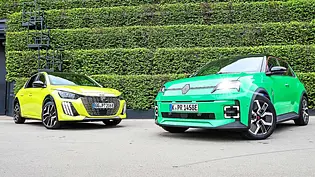 Gruppenbild mit den zwei elektrischen Kleinwagen Peugeot E-208 und Renault 5; Blick von schräg vorne auf die Autos. - Foto: Daniela Loof