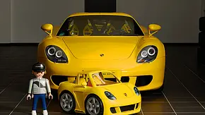 Das Bild zeigt einen Playmobil-Porsche-Carrera-GT samt Fahrerfigur vor einem realen Porsche GT. - Foto: Playmobil Das Bild zeigt einen Playmobil-Porsche-Carrera-GT samt Fahrerfigur vor einem realen Porsche GT. - Foto: Playmobil