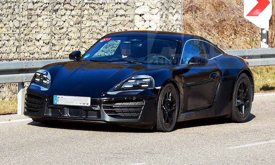 Porsche 718 Cayman Electric (2028) Blick von schräg vorne auf den fahrenden Erlkönig des Porsche 718 Cayman Electric (2028).