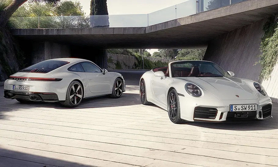 Das Porsche 911 Carrera S Facelift (2024) steht als Coupé und Cabrio vor einem Haus.
