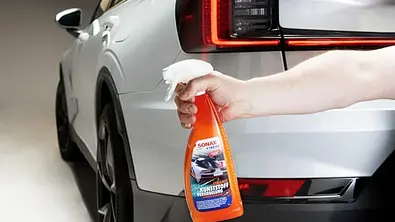 Heckansicht eines Autos mit Hand und Sonax Kunststoffversiegelung. - Foto: Sonax