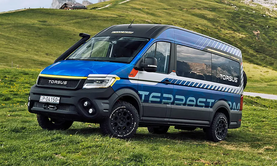 Torsus Terrastorm Camper 2025 in blauer Lackierung, Frontansicht mit Offroad-Bereifung auf einer Bergwiese.