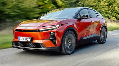 Der Toyota C-HR+ (2025) fährt auf einer Landstraße, von vorne links fotografiert. - Foto: Toyota