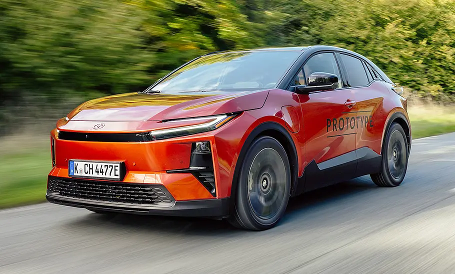 Toyota C-HR+ (2025) Der Toyota C-HR+ (2025) fährt auf einer Landstraße, von vorne links fotografiert.