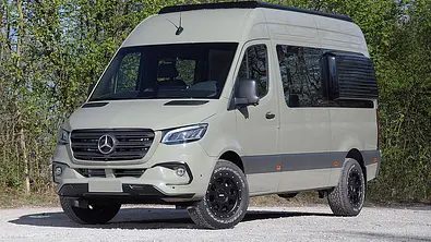 Der Mercedes Sprinter von Vansports steht auf einem Schotterparkplatz, von vorne links fotografiert. - Foto: Vansports