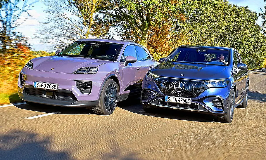 Porsche Macan Electric/Mercedes EQE SUV Blick von schräg vorne auf die fahrenden Porsche Macan Electric und Mercedes EQE SUV.