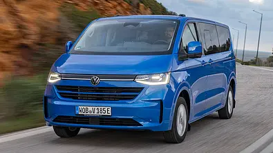 VW E-Caravelle (2025) fährt auf der Straße, Ansicht von vorne links. - Foto: VW