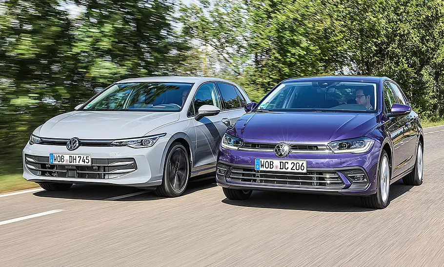VW Golf und VW Polo fahren nebeneinander auf einer Landstraße, von vorne fotografiert.