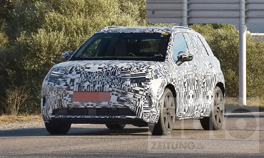 Der VW ID. Cross (2026) fährt als Erlkönig auf einer öffentlichen Straße, von vorne links fotografiert.