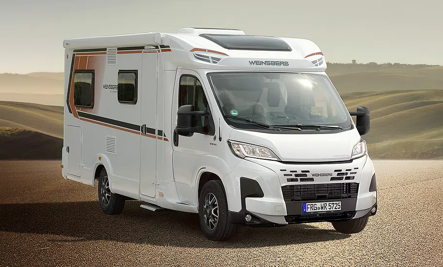 Weinsberg CaraCompact Edition Pepper (2026) steht auf einer Anhöhe, im Hintergrund Ausblick auf Felder. Ansicht des Fahrzeugs von vorne rechts.