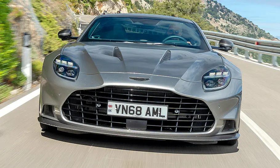 Der Aston Martin Vanquish (2024) fahrend auf einer Straße mit frontaler Ansicht.