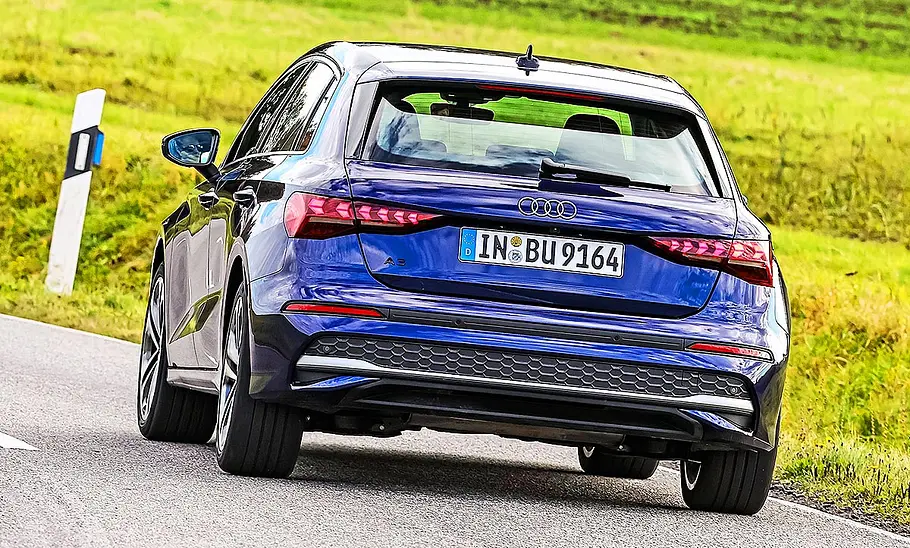 Blick von hinten auf den fahrenden Audi A3 auf einer Landstraße.