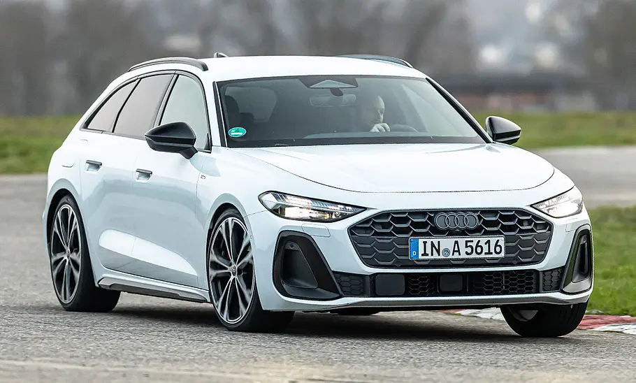 Der Audi A5 Avant fährt auf einer Rennstrecke durch eine Linkskurve, von vorne rechts fotografiert.