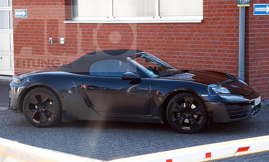 Ein Audi TT-Mule mit der Karosserie eines Porsche 718 fährt über einen Parkplatz, von rechts fotografiert.