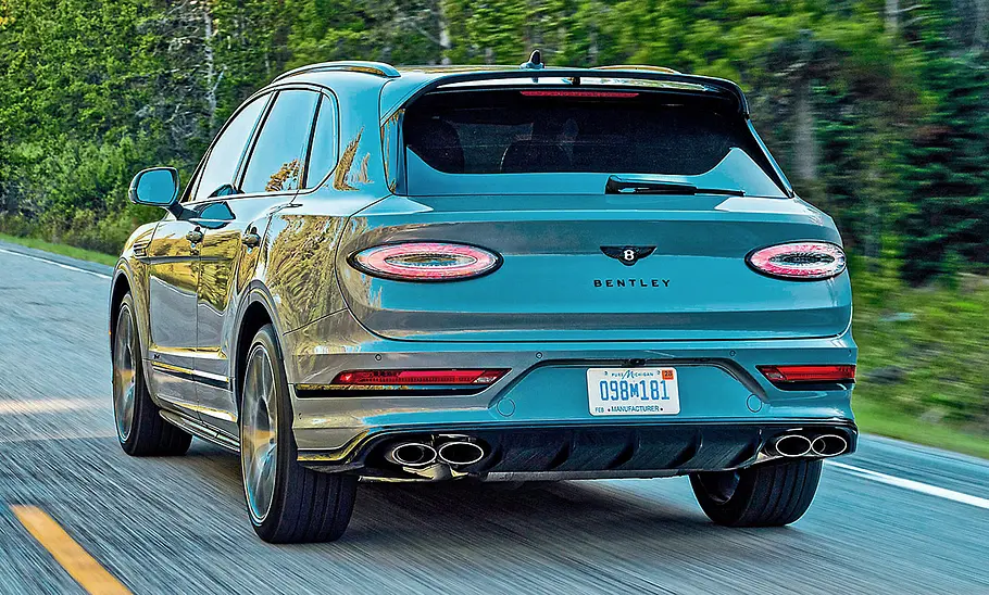 Bentley Bentayga Speed (2025) Bentley Bentayga Speed (2025) fährt auf einer Landstraße, Ansicht von hinten links.