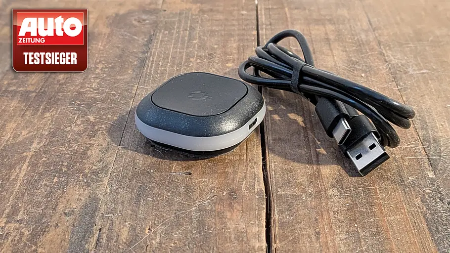 Tomtom Tom Blitzerwarner mit Ladekabel auf einem Holztisch.