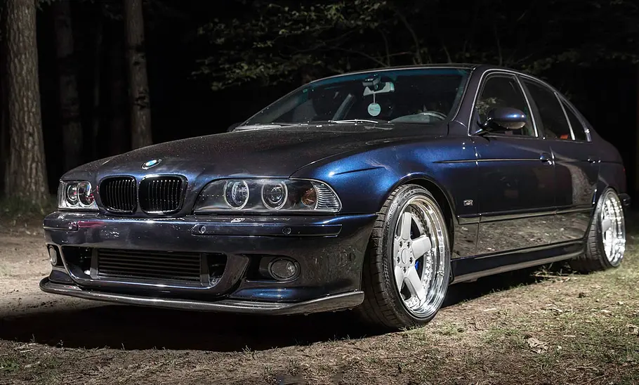 Getunter BMW 5er E39 mit Toyota-Motor im Wald, fotografiert von schräg vorne.