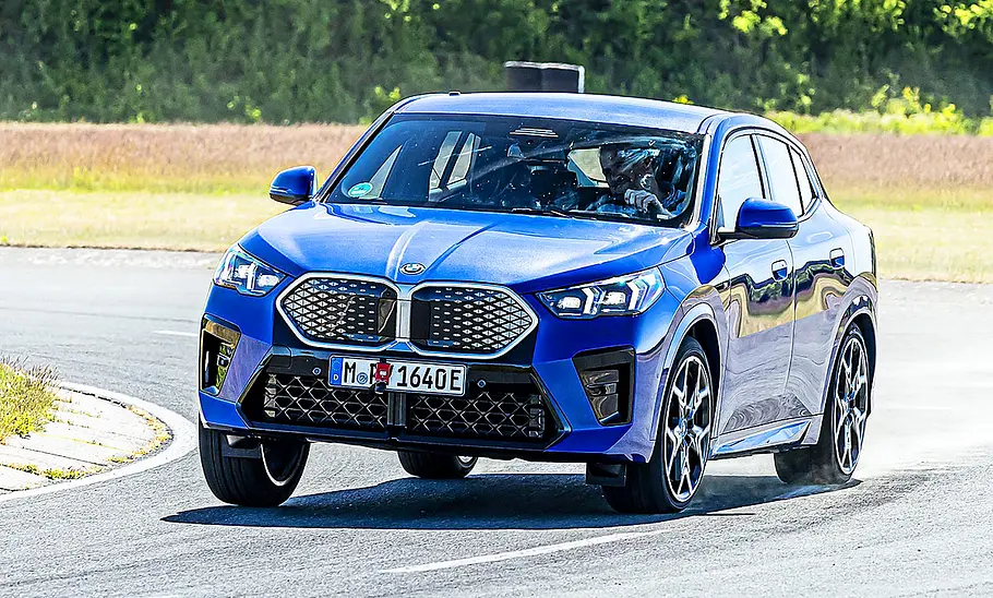 Blick von schräg vorne auf den fahrenden BMW iX2.