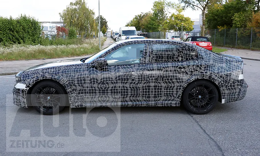 Der BMW M3 (2027) fährt als Erlkönig auf einer Straße, von links fotografiert.