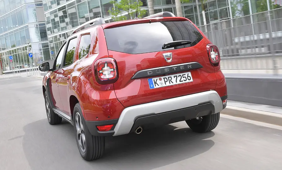 Der Dacia Duster (2018) fährt durch eine Stadt. von hinten links fotografiert.