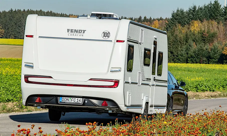 Fendt Caravan Apero 560 SKM (2024) Fendt Caravan Apero 560 SKM (2024) wird von einem Auto über eine Nebenstraße bewegt.