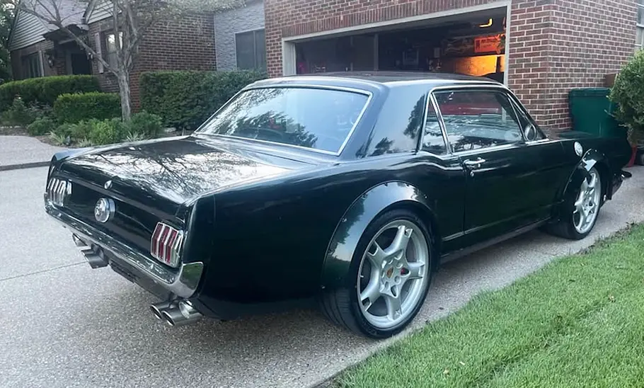 Restomod-Mix aus Ford Mustang und Porsche 911 in einer Einfahrt, fotografiert von schräg hinten.