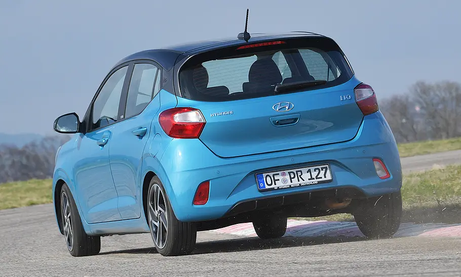 Der Hyundai i10 (2019) fährt durch eine Rechtskurve, von hinten links fotografiert.